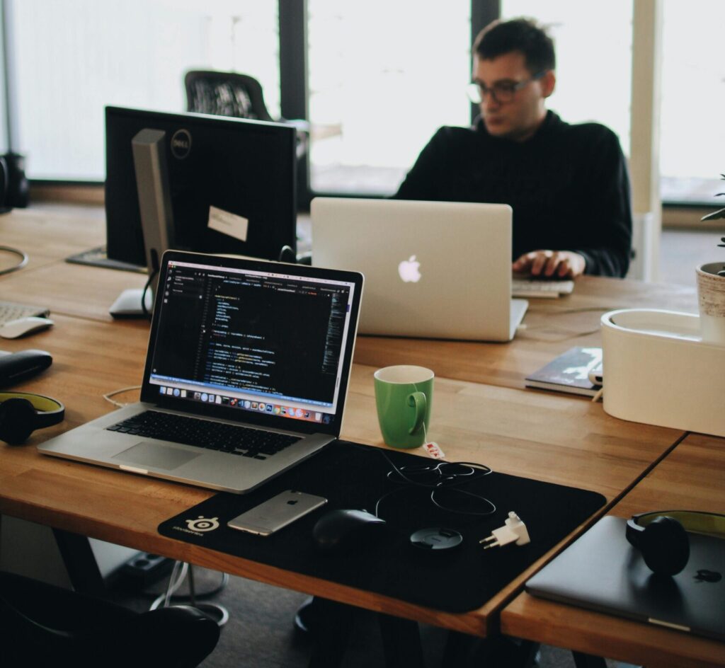 A web developer working on code in a modern office setting with multiple devices.