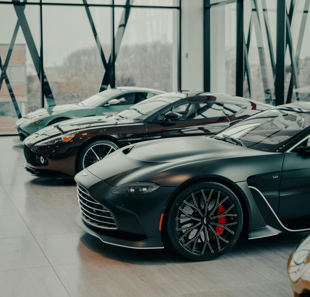 A collection of sleek luxury sports cars displayed in a contemporary showroom with large glass windows.