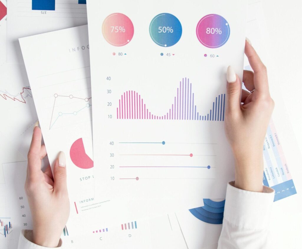 Close-up of hands analyzing colorful business data reports in an office setting.